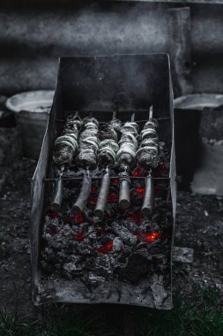 Alacakaranlıkta kömür ızgarası ve şiş et. Açık hava yemekleri, arka bahçe piknik atmosferi ve sokak yemekleri kültürü.