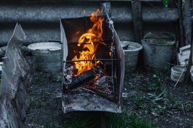Kötü yaşam koşullarında ısıtmak ya da pişirmek için kullanılan metal bir kapta ateş açın. Kentsel yoksulluğu, yer değiştirmeyi ve kriz ortamlarında hayatta kalmayı yansıtıyor