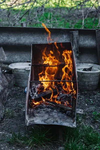 Kötü yaşam koşullarında ısıtmak ya da pişirmek için kullanılan metal bir kapta ateş açın. Kentsel yoksulluğu, yer değiştirmeyi ve kriz ortamlarında hayatta kalmayı yansıtıyor
