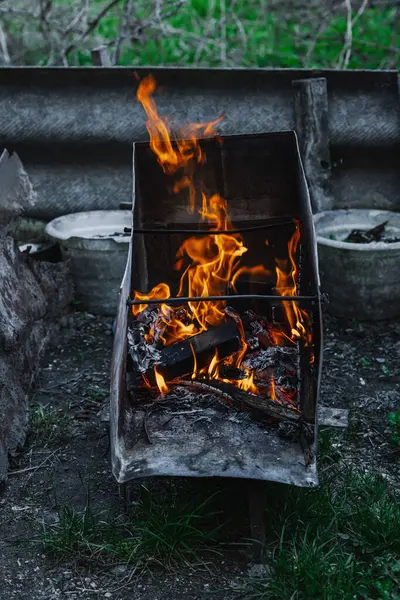 Kötü yaşam koşullarında ısıtmak ya da pişirmek için kullanılan metal bir kapta ateş açın. Kentsel yoksulluğu, yer değiştirmeyi ve kriz ortamlarında hayatta kalmayı yansıtıyor