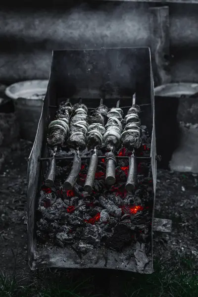 Alacakaranlıkta kömür ızgarası ve şiş et. Açık hava yemekleri, arka bahçe piknik atmosferi ve sokak yemekleri kültürü.