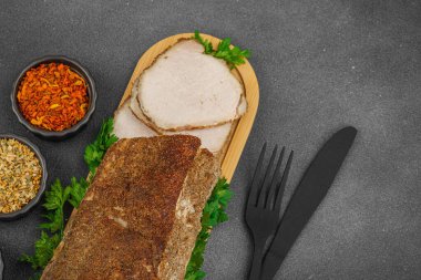 Lezzetli baharatlarla servis edilen yüksek proteinli domuz filetosu. Yemek fotoğrafçılığı için tasarlanmış. Keto ve paleo diyetleri için uygun, siyah taş arka plan, üst görünüm