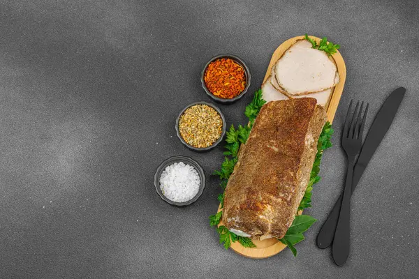 Lezzetli baharatlarla servis edilen yüksek proteinli domuz filetosu. Yemek fotoğrafçılığı için tasarlanmış. Keto ve paleo diyetleri için uygun, siyah taş arka plan, üst görünüm