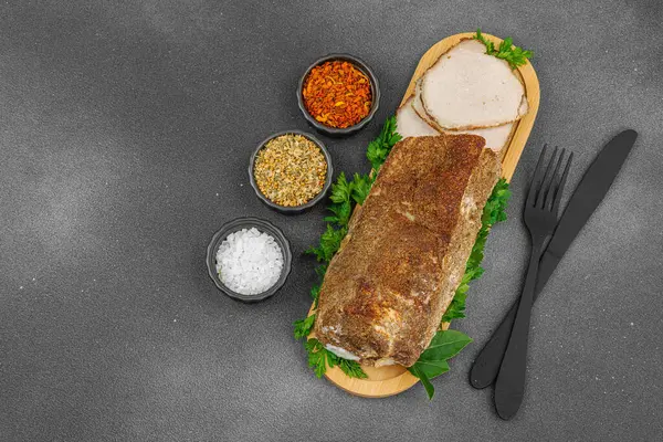Lezzetli baharatlarla servis edilen yüksek proteinli domuz filetosu. Yemek fotoğrafçılığı için tasarlanmış. Keto ve paleo diyetleri için uygun, siyah taş arka plan, üst görünüm