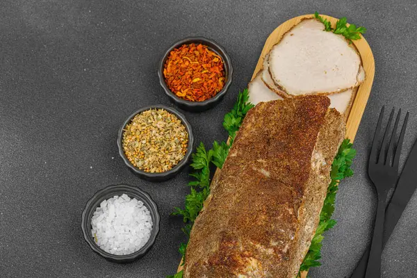 Lezzetli baharatlarla servis edilen yüksek proteinli domuz filetosu. Yemek fotoğrafçılığı için tasarlanmış. Keto ve paleo diyetleri için uygun, siyah taş arka plan, üst görünüm