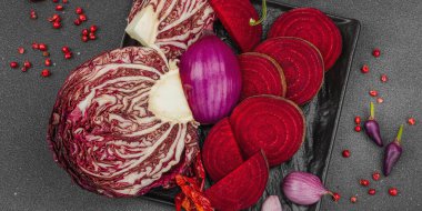 Modern bitki temelli sağlıklı aşçılık tarzı. Düz kırmızı pancar kökü, radicchio, kırmızı biber, kırmızı soğan, arpacık soğanı ve pembe karabiberlerden oluşan düz bir arkaplan, pankart biçimi.