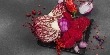 Modern bitki temelli sağlıklı aşçılık tarzı. Düz kırmızı pancar kökü, radicchio, kırmızı biber, kırmızı soğan, arpacık soğanı ve pembe karabiberlerden oluşan düz bir arkaplan, pankart biçimi.