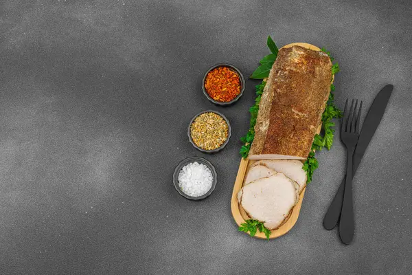 Lezzetli baharatlarla servis edilen yüksek proteinli domuz filetosu. Yemek fotoğrafçılığı için tasarlanmış. Keto ve paleo diyetleri için uygun, siyah taş arka plan, üst görünüm