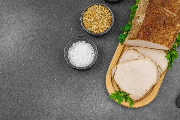 Lezzetli baharatlarla servis edilen yüksek proteinli domuz filetosu. Yemek fotoğrafçılığı için tasarlanmış. Keto ve paleo diyetleri için uygun, siyah taş arka plan, üst görünüm