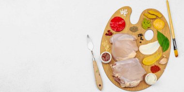 Çiğ tavuk butları, renkli baharatlar ve ahşap bir palette sos ile yaratıcı mutfak konsepti. Aşçıyı gurme mutfağında, afiş formatında temsil eden yemek sanatı fikri