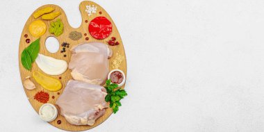 Çiğ tavuk butları, renkli baharatlar ve ahşap bir palette sos ile yaratıcı mutfak konsepti. Aşçıyı gurme mutfağında, afiş formatında temsil eden yemek sanatı fikri