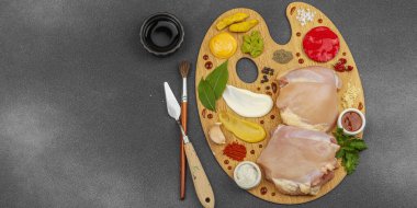 Çiğ tavuk butları, renkli baharatlar ve ahşap bir palette sos ile yaratıcı mutfak konsepti. Aşçıyı gurme mutfağında, afiş formatında temsil eden yemek sanatı fikri