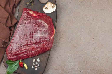 Tahta kesme tahtasının üzerinde çeşitli baharatlarla taze çiğ biftek. Et hazırlama, gurme pişirme ya da yemek tasarımı için mutfak konsepti.