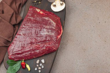 Tahta kesme tahtasının üzerinde çeşitli baharatlarla taze çiğ biftek. Et hazırlama, gurme pişirme ya da yemek tasarımı için mutfak konsepti.