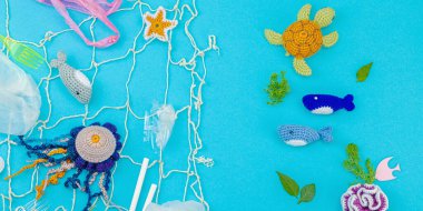 Dünya Okyanus Günü, su kirliliği farkındalığı ve çevresel eğitim görselleri. El yapımı tığ işi deniz hayvanları tek kullanımlık plastik eşyalar ve ağ, mavi arkaplan, deri döşeme, pankart formatında kapana kısıldılar.