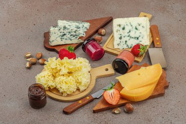 Çilekli, fındıklı ve reçelli peynir çeşitleri. Tahta tahtalarda Tete de Moine, Roquefort, Saint Agur ve Gouda 'yı içerir.