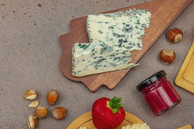 Çilekli, fındıklı ve reçelli peynir çeşitleri. Tahta tahtalarda Tete de Moine, Roquefort, Saint Agur ve Gouda 'yı içerir.