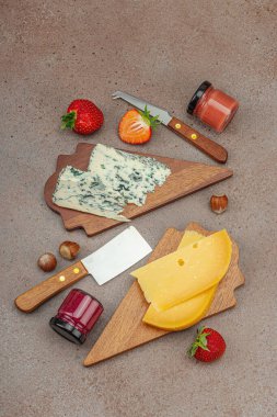 Çilekli, fındıklı ve reçelli peynir çeşitleri. Tahta tahtalarda Tete de Moine, Roquefort, Saint Agur ve Gouda pankartlarını, pankart biçimini içerir