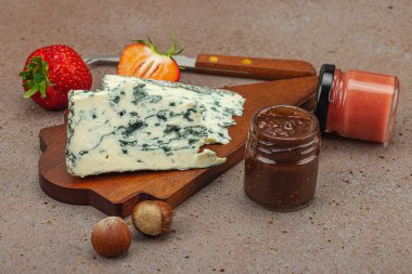 Çilekli, fındıklı ve reçelli peynir çeşitleri. Tahta tahtalarda Tete de Moine, Roquefort, Saint Agur ve Gouda pankartlarını, pankart biçimini içerir