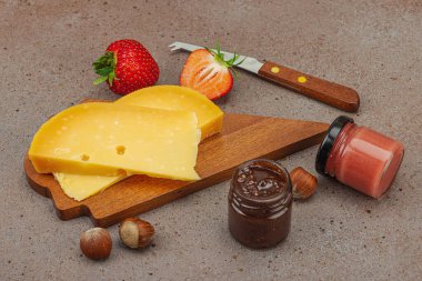 Çilekli, fındıklı ve reçelli peynir çeşitleri. Tahta tahtalarda Tete de Moine, Roquefort, Saint Agur ve Gouda pankartlarını, pankart biçimini içerir