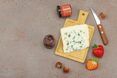 Çilekli, fındıklı ve reçelli peynir çeşitleri. Tahta tahtalarda Tete de Moine, Roquefort, Saint Agur ve Gouda 'yı içerir.