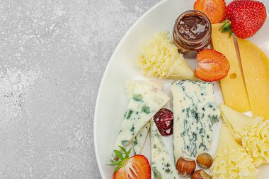 Çilekli, fındıklı ve reçelli peynir çeşitleri. Tahta tahtalarda Tete de Moine, Roquefort, Saint Agur ve Gouda 'yı içerir.