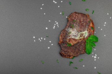 Eritilmiş tereyağlı ızgara biftek ve koyu arka planda otlar, yüksek protein öğünleri konsepti. Mangal stili, piknik yemeği, düz yatak, üst manzara.