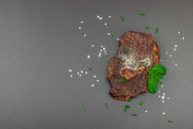 Eritilmiş tereyağlı ızgara biftek ve koyu arka planda otlar, yüksek protein öğünleri konsepti. Mangal stili, piknik yemeği, düz yatak, üst manzara.