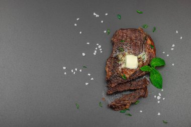 Eritilmiş tereyağlı ızgara biftek ve koyu arka planda otlar, yüksek protein öğünleri konsepti. Mangal stili, piknik yemeği, düz yatak, üst manzara.