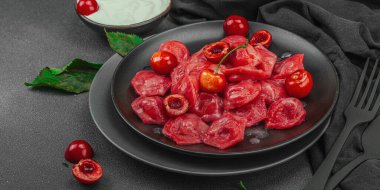 Koyu bir tabakta taze kiraz ve nane yapraklarıyla servis edilen ekşi kremalı kirazlı hamur tatlısı. Geleneksel Ukrayna tatlı tatlısı, düzlük, afiş biçimi