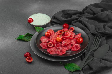 Koyu bir tabakta taze kiraz ve nane yapraklarıyla servis edilen ekşi kremalı kirazlı hamur tatlısı. Geleneksel Ukrayna tatlı tatlısı, düzlük, kopyalama alanı