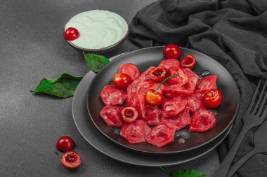 Koyu bir tabakta taze kiraz ve nane yapraklarıyla servis edilen ekşi kremalı kirazlı hamur tatlısı. Geleneksel Ukrayna tatlı tatlısı, düzlük, kopyalama alanı