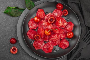 Koyu bir tabakta taze kiraz ve nane yapraklarıyla servis edilen ekşi kremalı kirazlı hamur tatlısı. Geleneksel Ukrayna tatlı tatlısı, düz uzanma, üst manzara