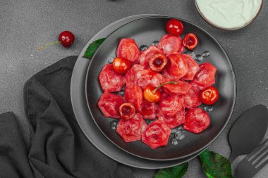 Koyu bir tabakta taze kiraz ve nane yapraklarıyla servis edilen ekşi kremalı kirazlı hamur tatlısı. Geleneksel Ukrayna tatlı tatlısı, düz uzanma, üst manzara