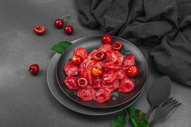 Koyu bir tabakta taze kiraz ve nane yapraklarıyla servis edilen ekşi kremalı kirazlı hamur tatlısı. Geleneksel Ukrayna tatlı tatlısı, düzlük, kopyalama alanı