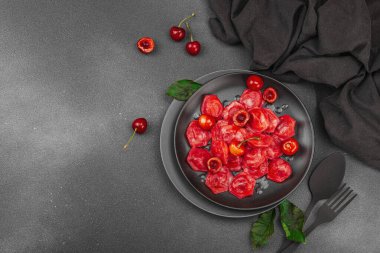 Koyu bir tabakta taze kiraz ve nane yapraklarıyla servis edilen ekşi kremalı kirazlı hamur tatlısı. Geleneksel Ukrayna tatlı tatlısı, düz uzanma, üst manzara