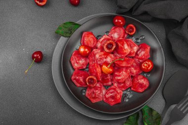 Koyu bir tabakta taze kiraz ve nane yapraklarıyla servis edilen ekşi kremalı kirazlı hamur tatlısı. Geleneksel Ukrayna tatlı tatlısı, düz uzanma, üst manzara