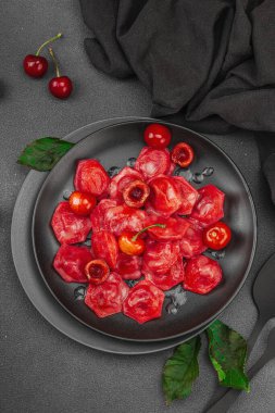 Koyu bir tabakta taze kiraz ve nane yapraklarıyla servis edilen ekşi kremalı kirazlı hamur tatlısı. Geleneksel Ukrayna tatlı tatlısı, düz uzanma, üst manzara