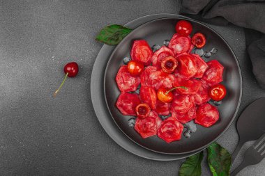 Koyu bir tabakta taze kiraz ve nane yapraklarıyla servis edilen ekşi kremalı kirazlı hamur tatlısı. Geleneksel Ukrayna tatlı tatlısı, düz uzanma, üst manzara