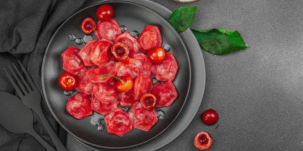 Koyu bir tabakta taze kiraz ve nane yapraklarıyla servis edilen ekşi kremalı kirazlı hamur tatlısı. Geleneksel Ukrayna tatlı tatlısı, düzlük, afiş biçimi