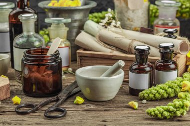 Verbascum çiçekleri, bitkisel kavanozlar, antika aletler ve ahşap masada havan topuyla kırsal eczacılık sahnesi. Alternatif tıp, sağlıklı yaşam tarzı konsepti, kapatın.