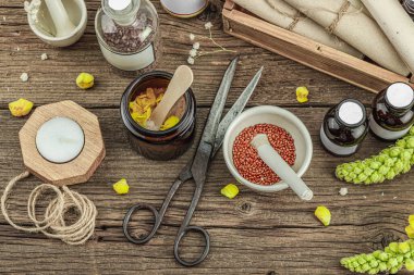 Verbascum çiçekleri, bitkisel kavanozlar, antika aletler ve ahşap masada havan topuyla kırsal eczacılık sahnesi. Alternatif tıp, sağlıklı yaşam tarzı konsepti, üst bakış.