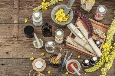 Verbascum çiçekleri, bitkisel kavanozlar, antika aletler ve ahşap masada havan topuyla kırsal eczacılık sahnesi. Alternatif tıp, sağlıklı yaşam tarzı konsepti, üst bakış.