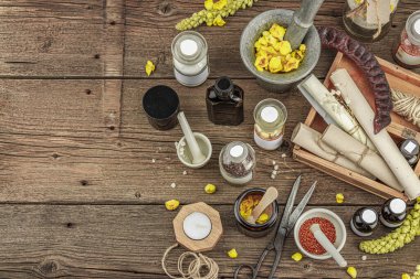 Verbascum çiçekleri, bitkisel kavanozlar, antika aletler ve ahşap masada havan topuyla kırsal eczacılık sahnesi. Alternatif tıp, sağlıklı yaşam tarzı konsepti, üst bakış.