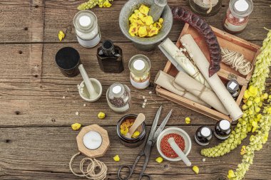 Verbascum çiçekleri, bitkisel kavanozlar, antika aletler ve ahşap masada havan topuyla kırsal eczacılık sahnesi. Alternatif tıp, sağlıklı yaşam tarzı konsepti, üst bakış.