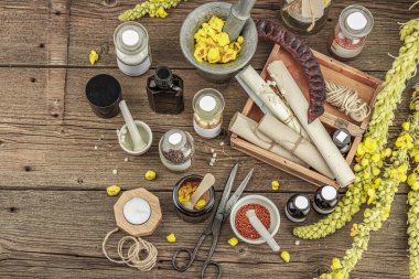 Verbascum çiçekleri, bitkisel kavanozlar, antika aletler ve ahşap masada havan topuyla kırsal eczacılık sahnesi. Alternatif tıp, sağlıklı yaşam tarzı konsepti, üst bakış.