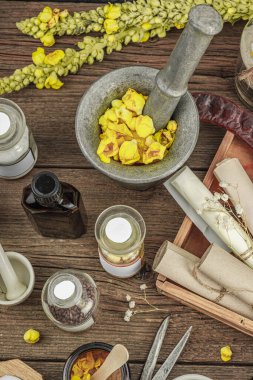 Verbascum çiçekleri, bitkisel kavanozlar, antika aletler ve ahşap masada havan topuyla kırsal eczacılık sahnesi. Alternatif tıp, sağlıklı yaşam tarzı konsepti, üst bakış.