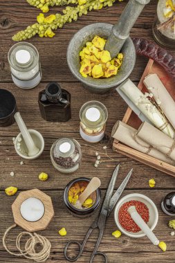 Verbascum çiçekleri, bitkisel kavanozlar, antika aletler ve ahşap masada havan topuyla kırsal eczacılık sahnesi. Alternatif tıp, sağlıklı yaşam tarzı konsepti, üst bakış.