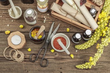 Verbascum çiçekleri, bitkisel kavanozlar, antika aletler ve ahşap masada havan topuyla kırsal eczacılık sahnesi. Alternatif tıp, sağlıklı yaşam tarzı konsepti, üst bakış.