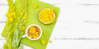 Bir fincan çiçekli ve yapraklı bitki çayı. Doğal ışık, alternatif tıp, antika şifalı bitkiler, ahşap arka plan, afiş biçimi